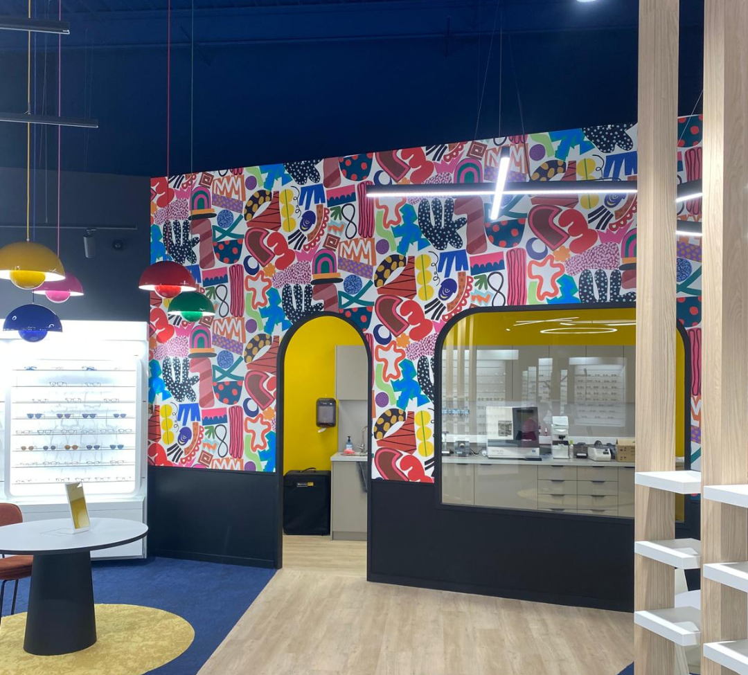 Mur décoré avec papier peint motif abstrait dans une boutique d’optique, réalisé par Marchand Décoration Château-Gontier.
